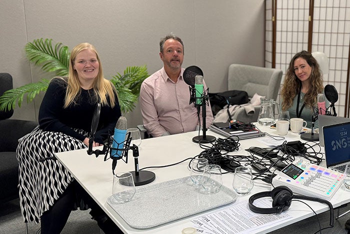 Three people sat around radio equipment 