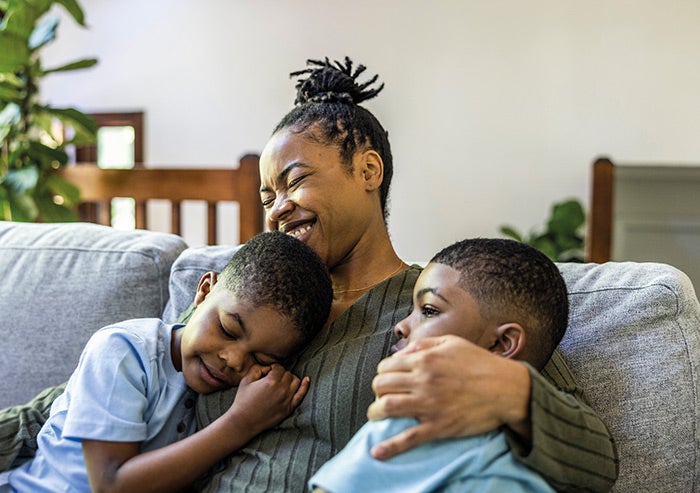 A mother and her two sons sitting together on a sofa