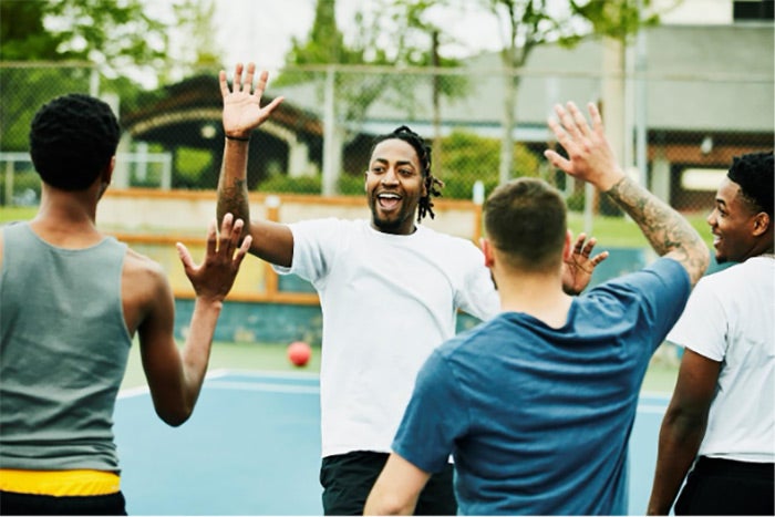 A group of youths giving each other high-fives following a game of basketball