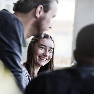 A woman, smiling and looking at a man