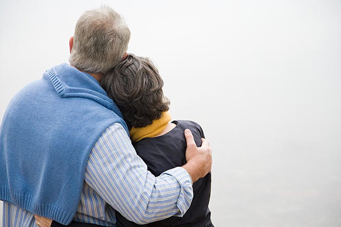 Two elderly people hugging 