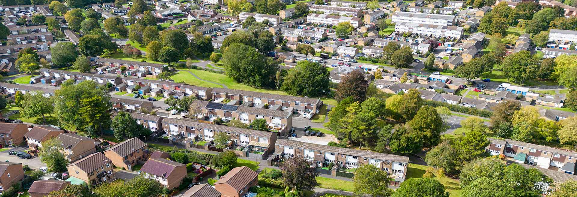 Aerial view of a suburban neighbourhood with homes, trees, and green spaces