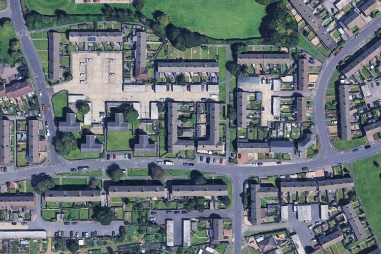 Aerial satellite view of a residential neighbourhood showing roads, houses and green spaces.