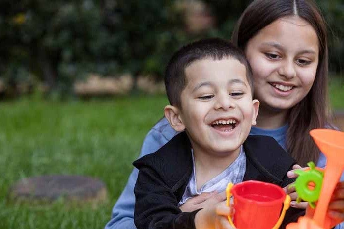 Two children smiling and playing with a toy