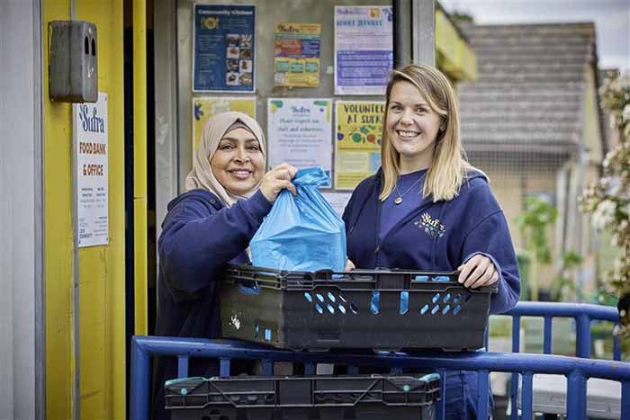 Two people smiling holding a bag of food