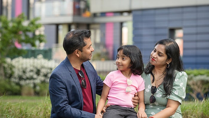 Family of three sitting together outdoors in a residential courtyard