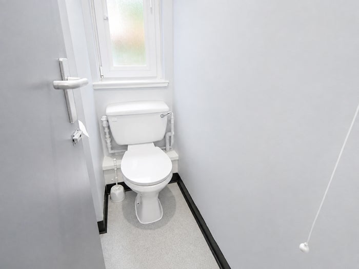Compact WC with toilet, white walls and frosted window.