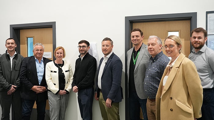 Group of people standing in a community centre hallway, arranged in a line and posing for a photograph