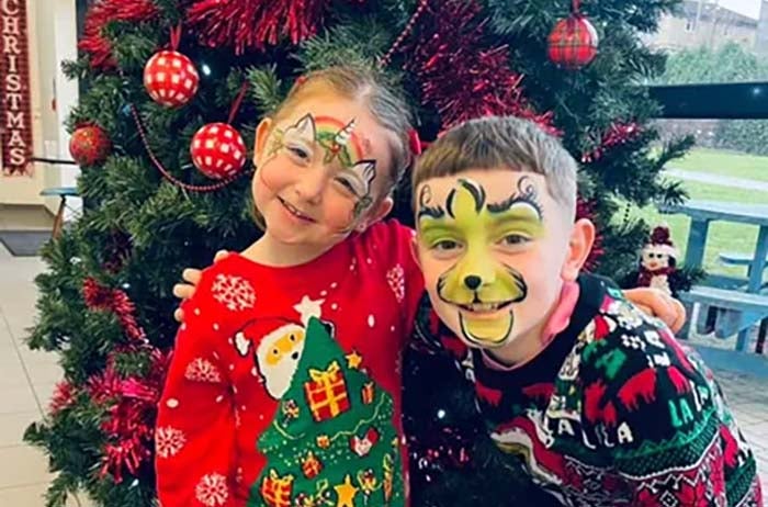 Two children with facepraint, standing in front of a Christmas tree