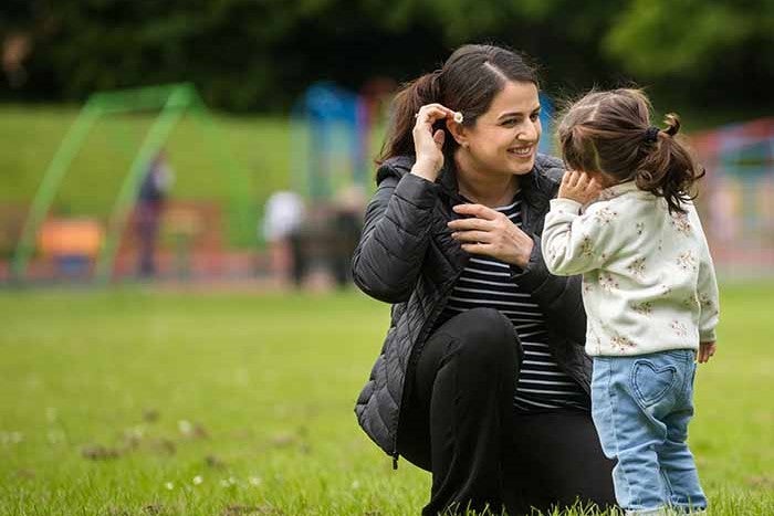 Women kneeling down to speak to little girl