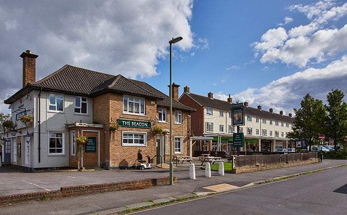 A pub next to a parade of shops with flats above them