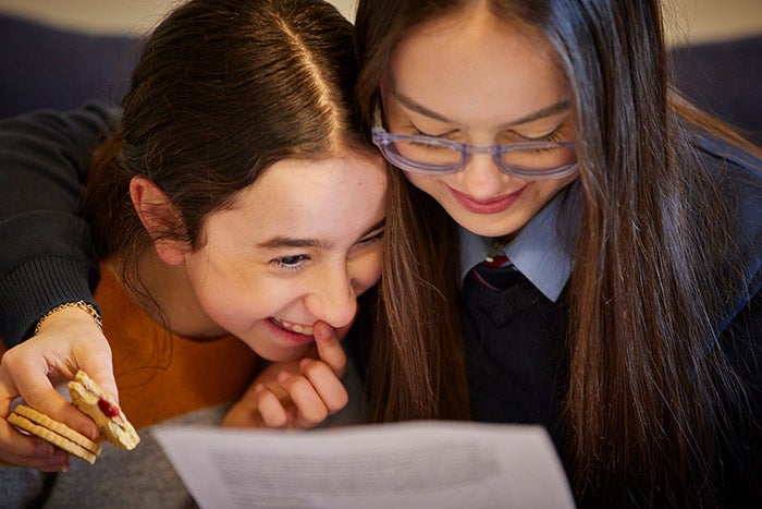 Two young girls reading information from a sheet of paper
