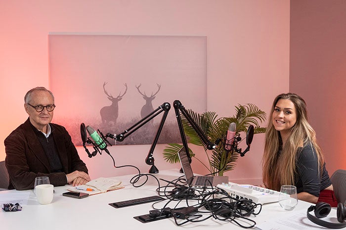 a man and a woman sitting in a radio booth, with equipment everywhere