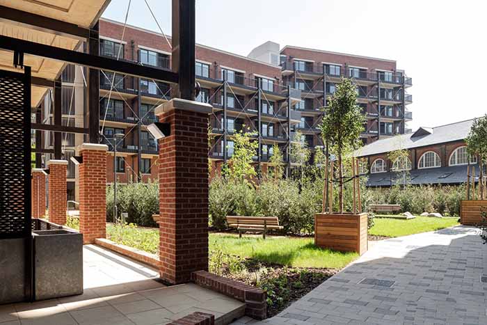 Communal green space within development with restored refectory in background.