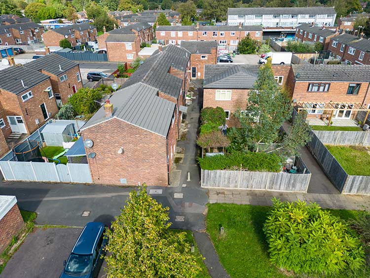 Aerial view of a residential neighbourhood with brick homes, private gardens, pedestrian pathways and shared green spaces.