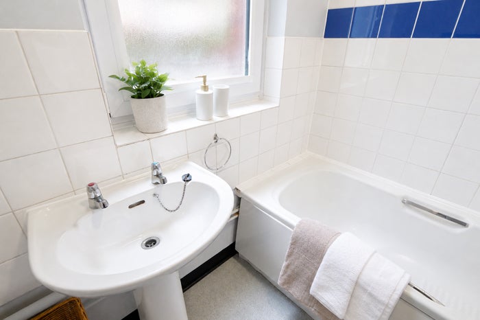 Bright bathroom featuring wash basin, bath with shower and tiled walls