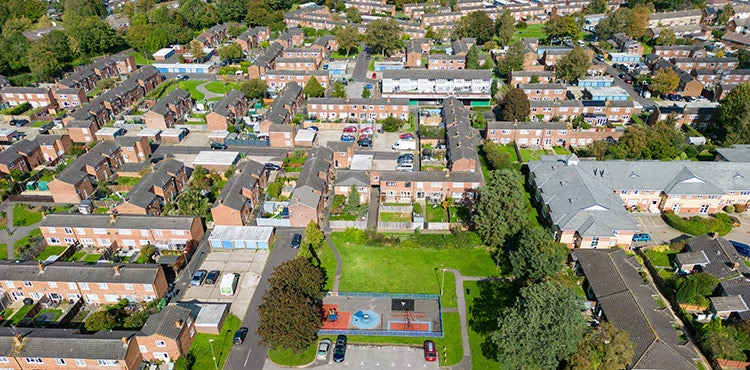 Aerial view of a residential neighbourhood with rows of brick homes, communal green space and a children's playground.