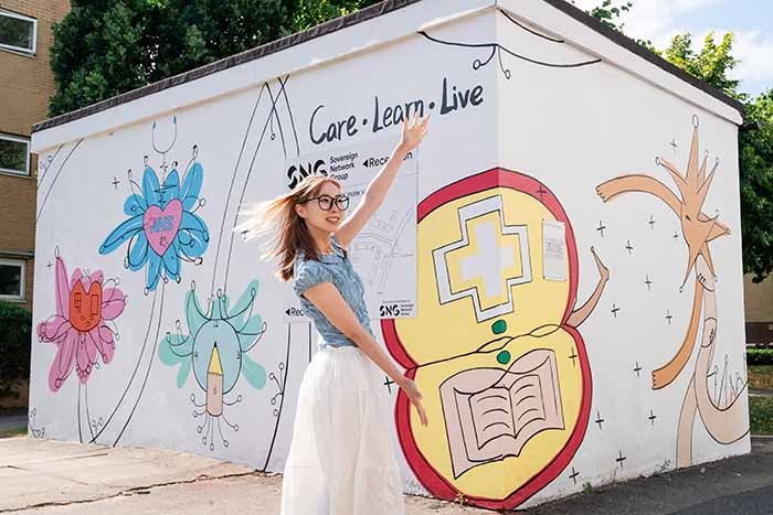 University of Westminster student Miguel Fons posing with her mural at Northwick Park.