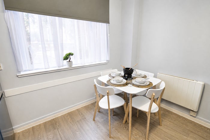 Dining area within the communal kitchen beside a large window
