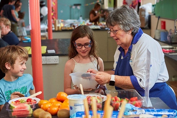 A lady leading an interactive cooking workshop activity with some children