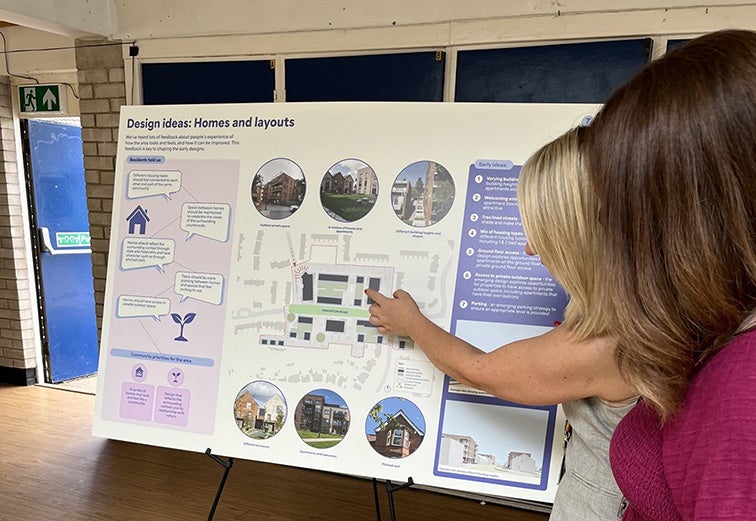 Community member reviewing proposed homes and site layout plans at a consultation event.