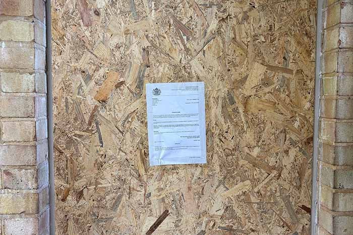 Closure notice on boarded up front door of closed property at Wenlock Court
