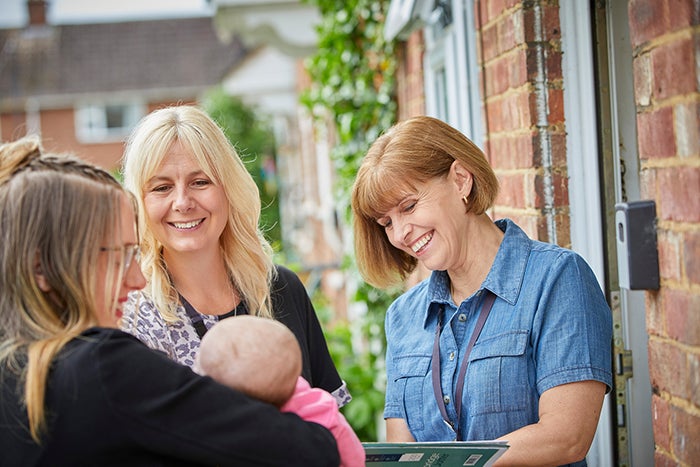 Two female housing officers talking to an SNG resident outside their home