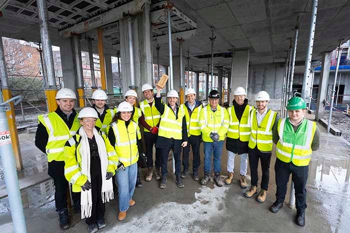A group of people on a building site, in high vis jackets and hard hats