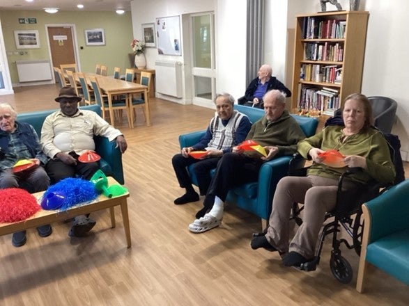 Photo of six older people sat in chairs taking part in the Reminiscence programme 