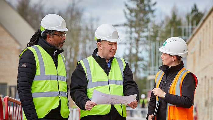 SNG employees wearing hi-vis jackets on a building site, talking to a developer partner