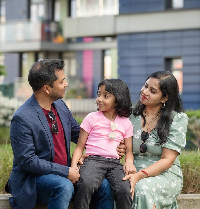 Family of three sitting together outdoors in a residential courtyard