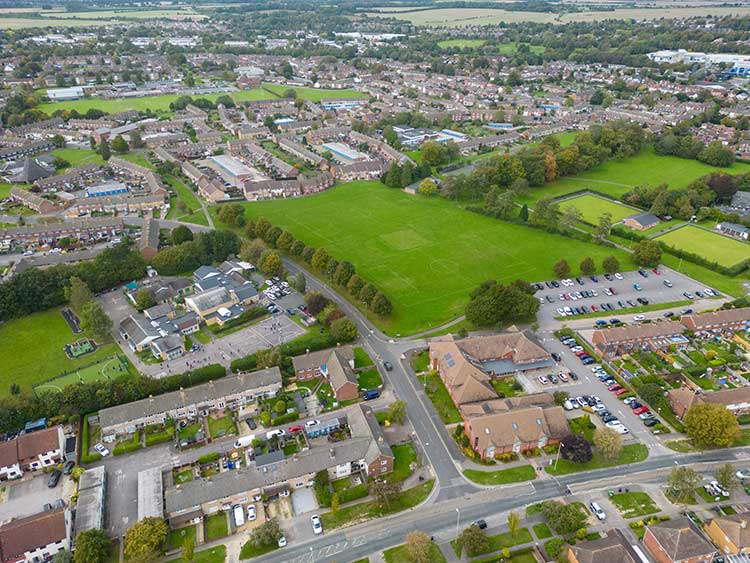 Aerial view of a neighbourhood with homes, open green fields and community spaces.