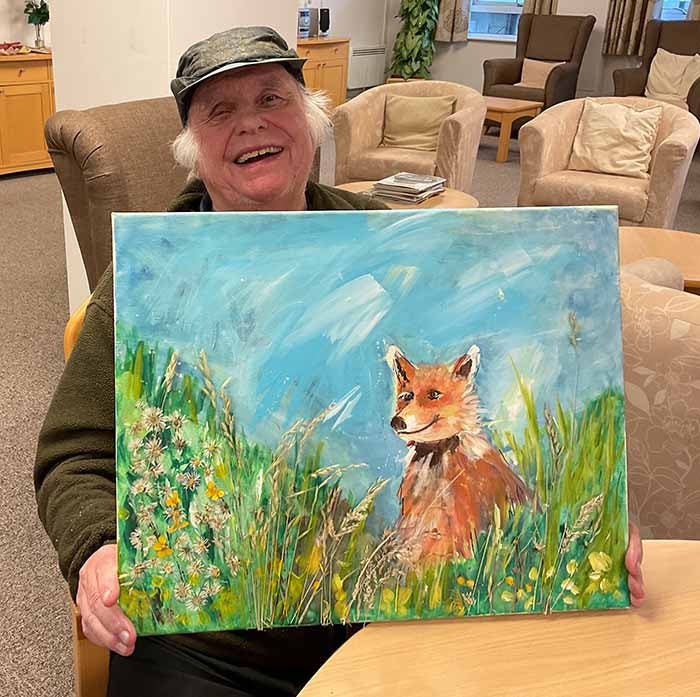 A woman holding a painting of a fox she painted