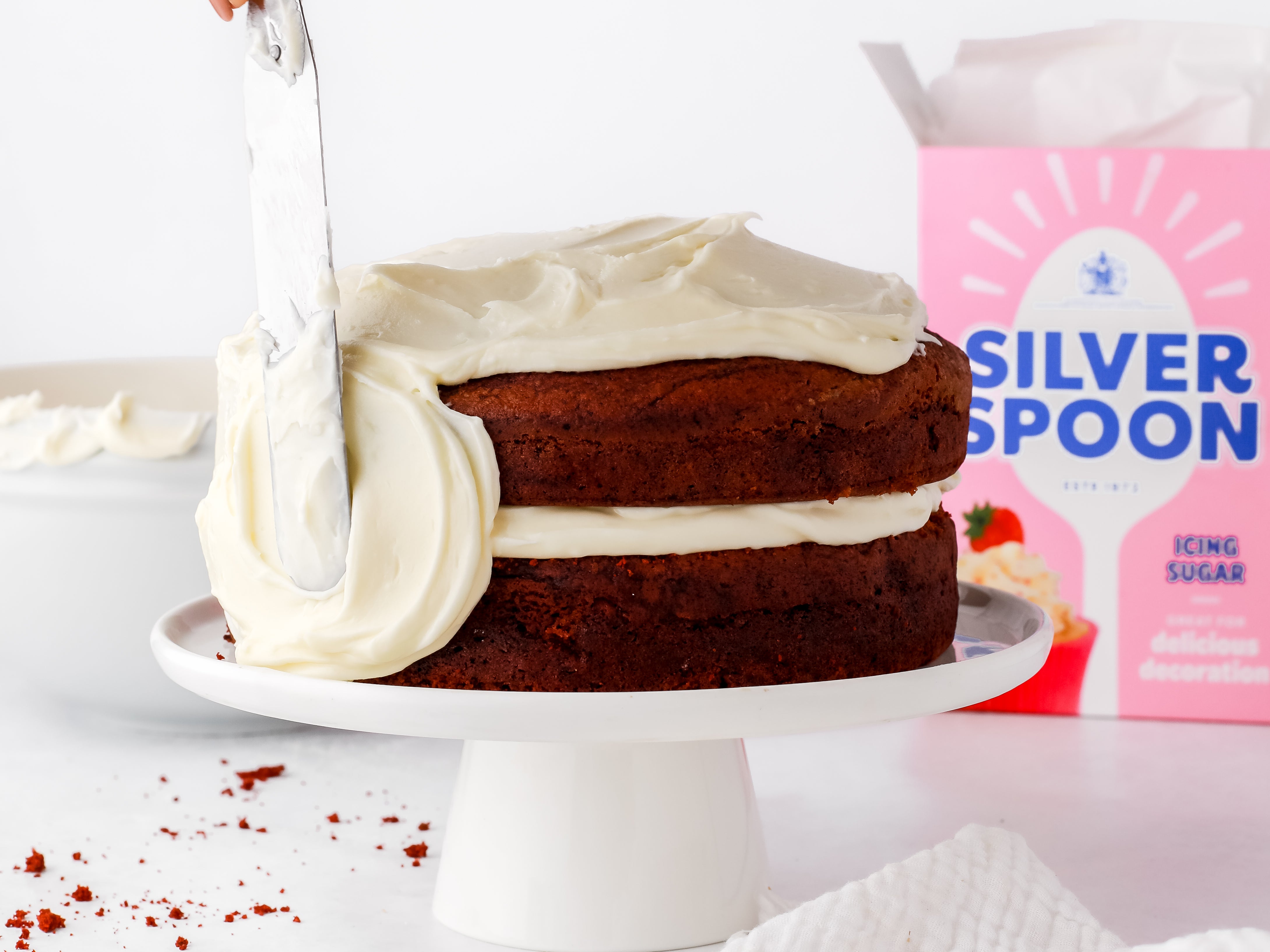 Buttercream being spread on to a red velvet cake