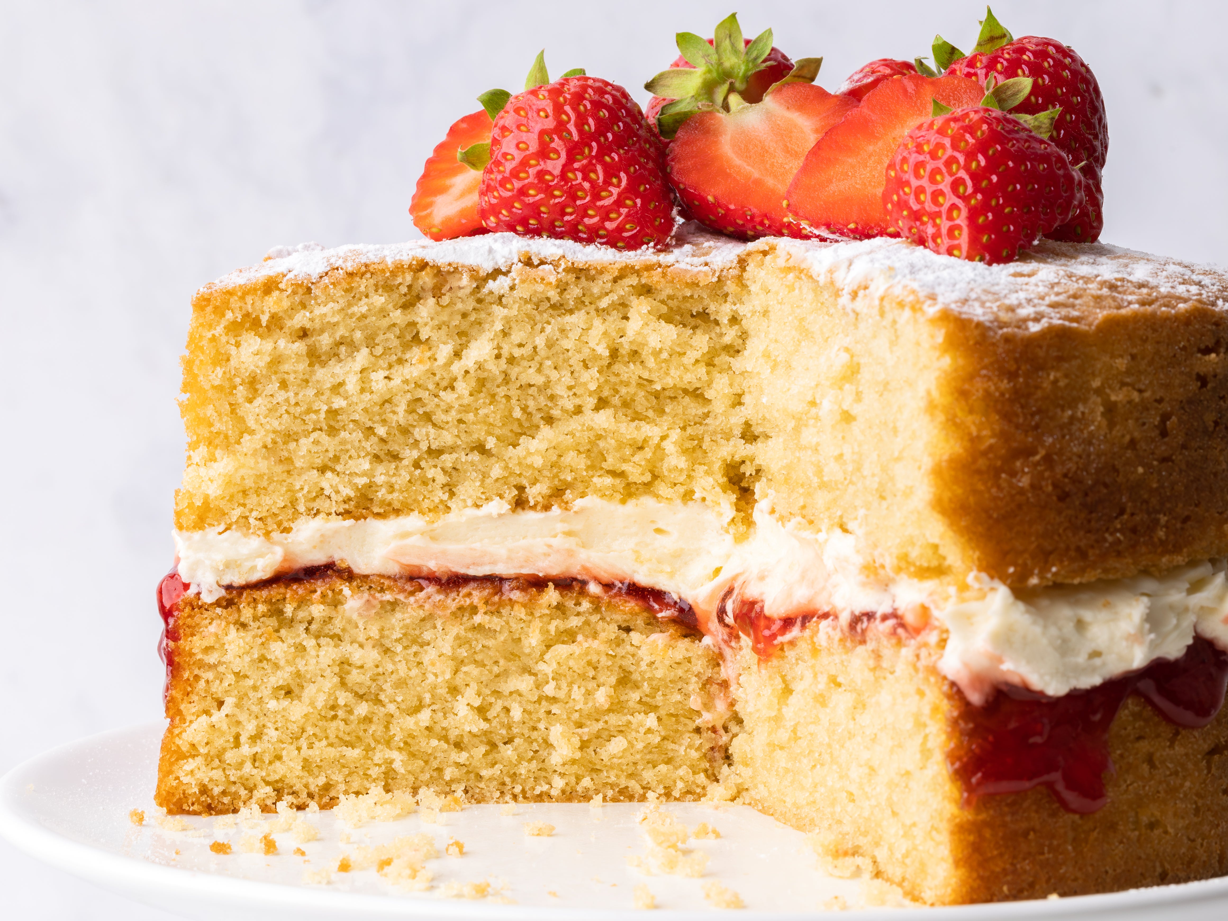 Victoria sponge with large slice removed and strawberries on top