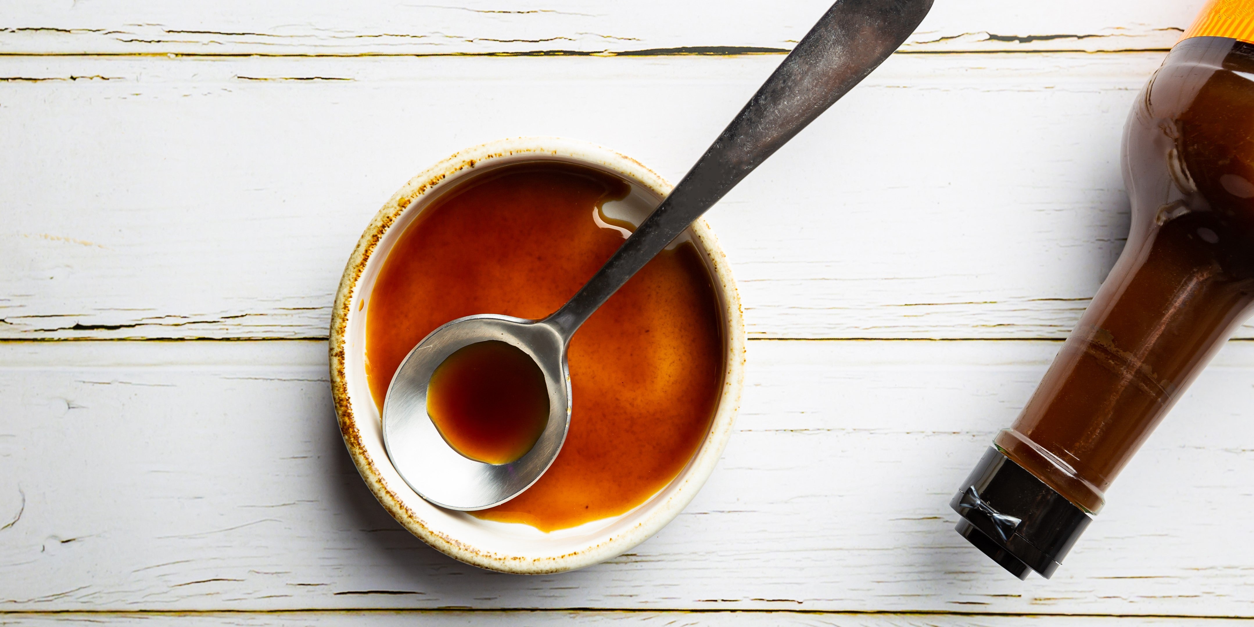 Worcestershire sauce in an earthenware bowl with a silver serving spoon