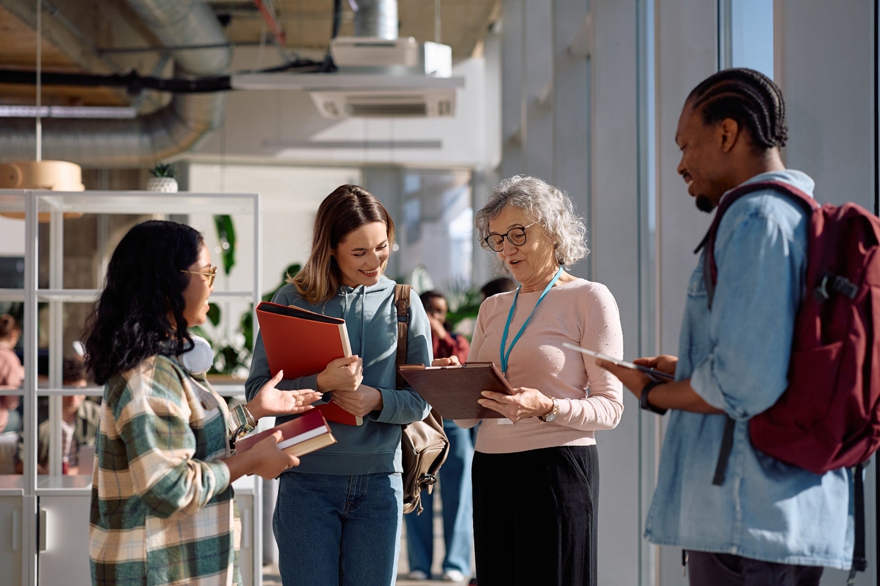 A group of four people standing together, looking at a notepad and smiling
