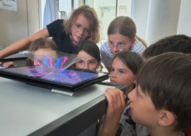 Gespannt blicken die Schülerinnen und Schüler auf das Tablet. (Foto: Deutsche Bildungsdirektion/Alexander Ulbricht)