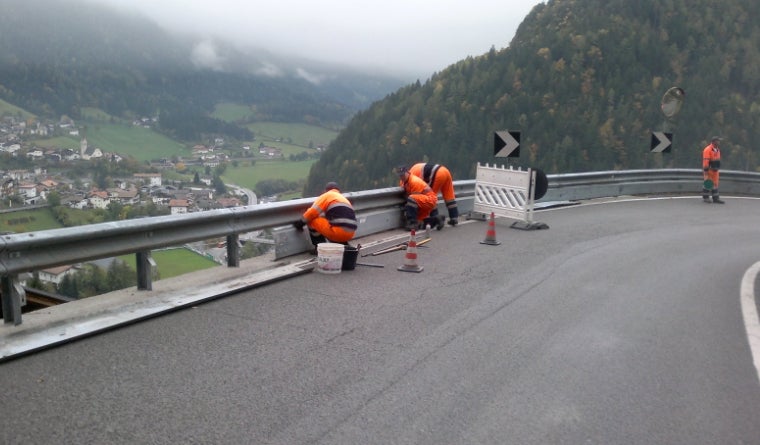 Straßenarbeiter beim Errichten von Schutzplanken mit Motorradschutz