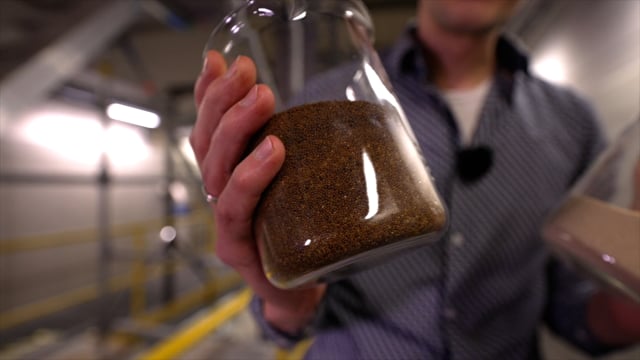 Medewerker van Evides laat een glazen pot vol kalkkorrels zien.