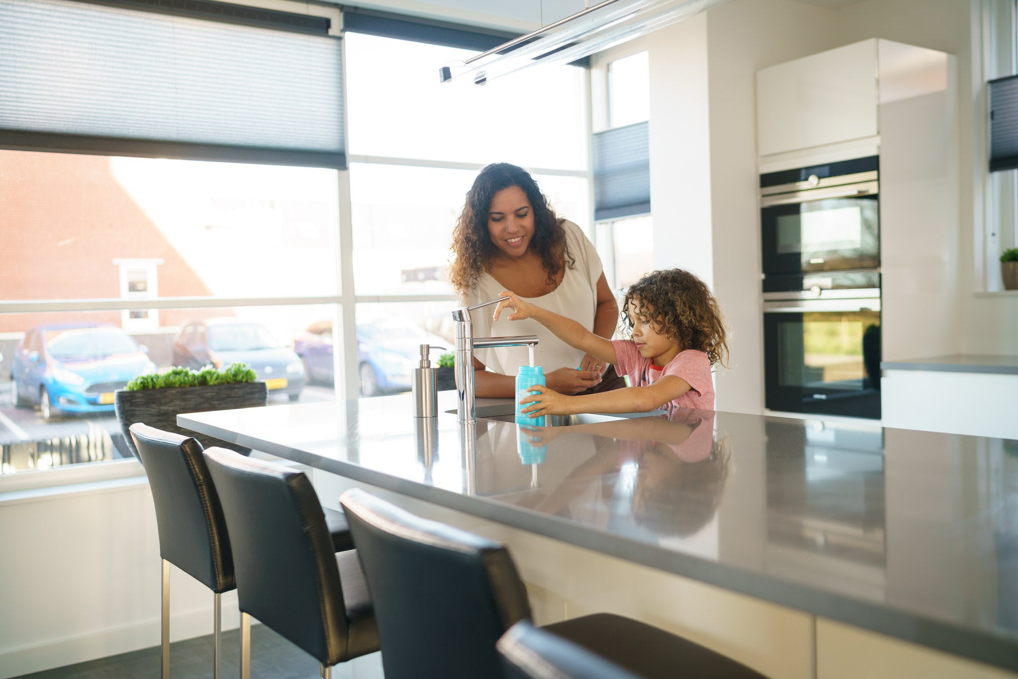 Kind en vrouw vullen bidon onder kraan