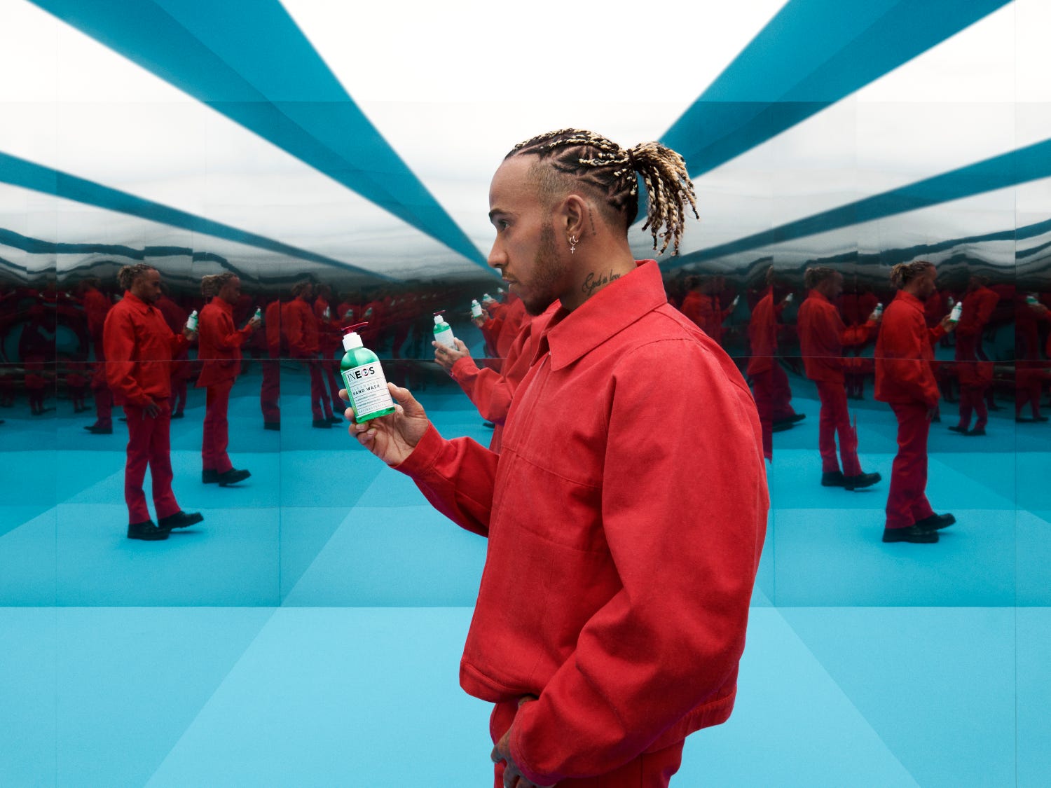 a photo of lewis hamilton in a red suit holding sanitiser in a room of mirrors