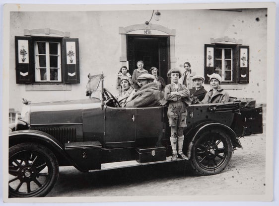 Franz Angerer und seine beiden Söhne im Fiat 501 vor dem Eingang des Hotels, im Hintergrund seine Frau Fanny geb. Aschberger und weitere Personen, um 1925.