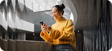 Image of a woman in a yellow shirt, holding a mobile phone.