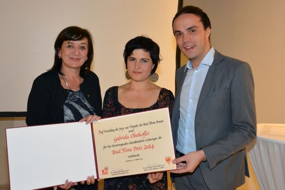 Auf dem Foto von links nach rechts zu sehen: In der Taxisgalerie in Innsbruck halten Tirols Landesrätin Beate Palfrader, die Preisträgerin Gabriela Oberkofler und Südtirols Landesrat Philipp Achammer die Preisurkunde. Foto: Land Südtirol, A. Pidner.