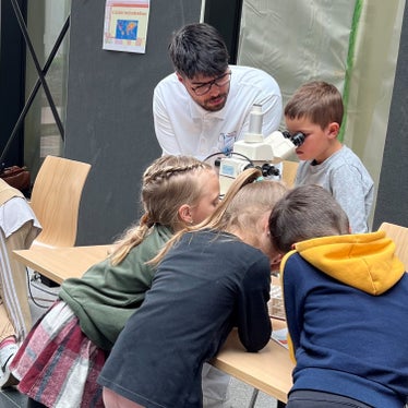 Dr. Raphael Pinti erklärt den Kindern das Mikroskop