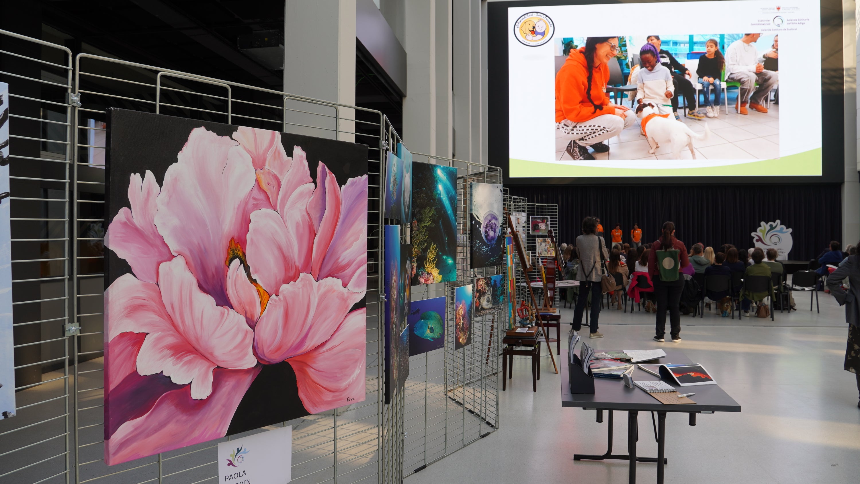 In Bozen präsentierten Mitarbeitende ihre Talente, im Vordergrund ein Bild der Krankenpflegerin Paola Garbin. Sozialassistentin Debora Turolla hielt einen einfühlsamen Vortrag über Pet Therapy. (Foto: Sabes)