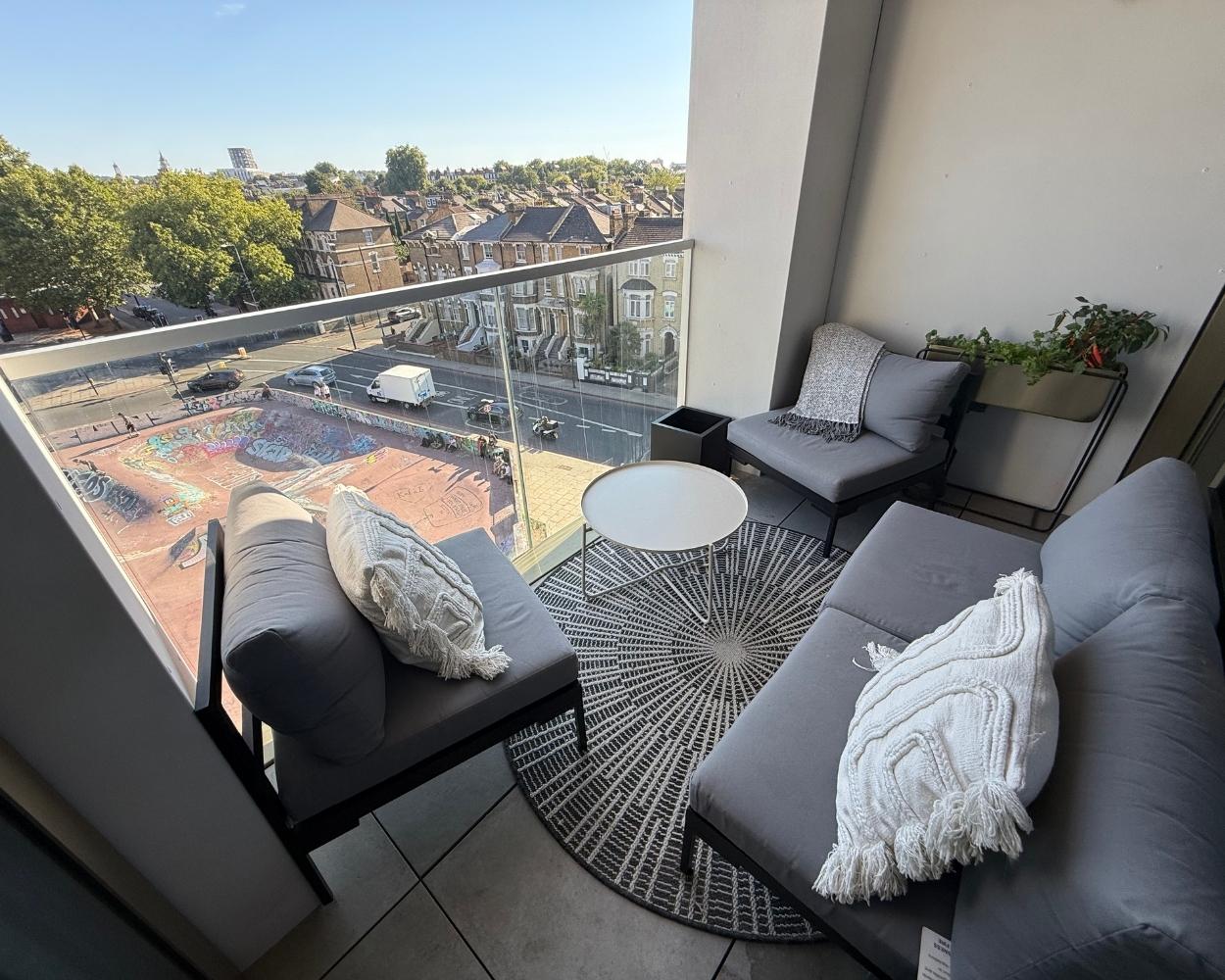 Photo of the balcony, featuring views over a row of houses, trees and a skate park