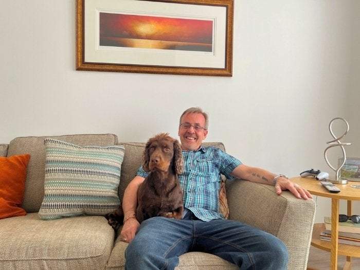 Paul relaxes on his sofa with his dog Reggie.