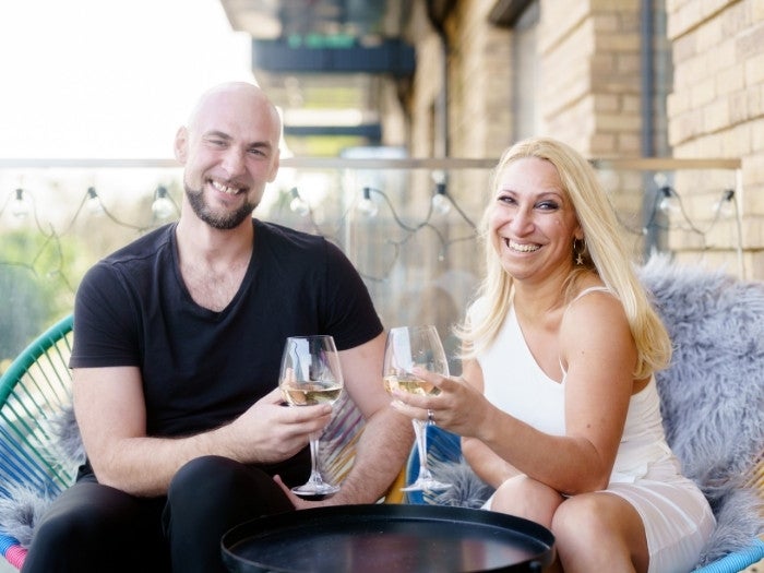 Domnita and Behjet sit on their balcony enjoying a glass of wine together.